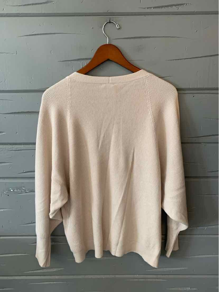 Solid beige women’s sweater with a soft knit texture, draped sleeves, and an asymmetrical hem.