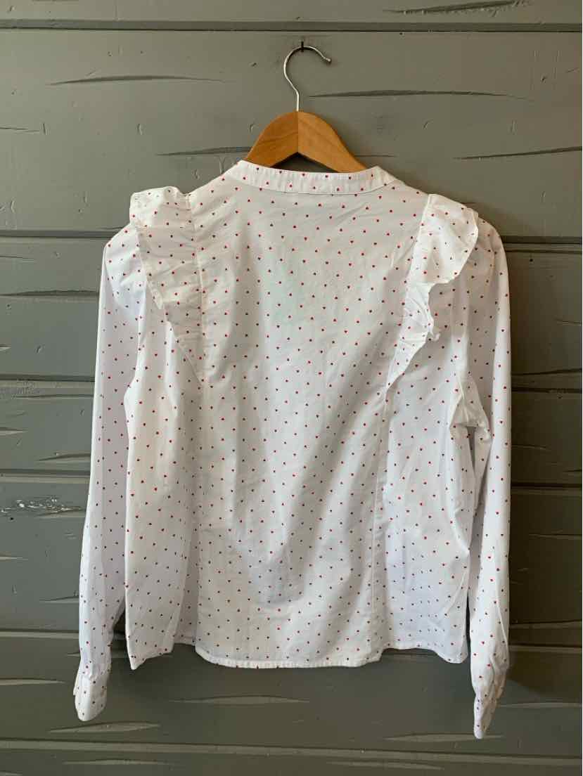 White long-sleeve blouse with small red and blue heart patterns, puffed shoulders, and buttoned cuffs.