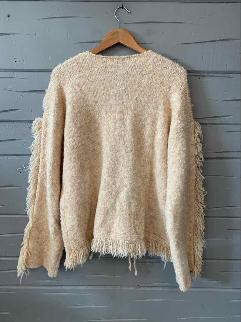 Tan fuzzy knit sweater with long sleeves and fringed details along the sides and hem.