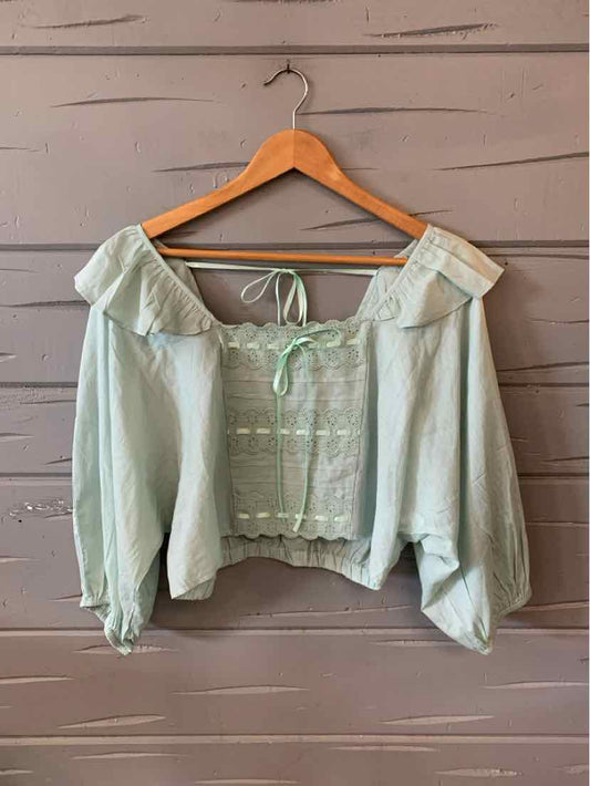 Mint green off-shoulder cropped blouse with ruffled neckline, puffed sleeves, and tie-front detailing.