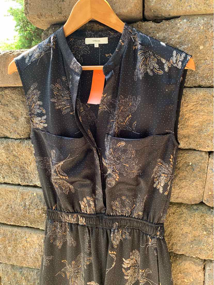 Black sleeveless blouse with metallic floral print, V-neck, front pockets, and cinched waist.
