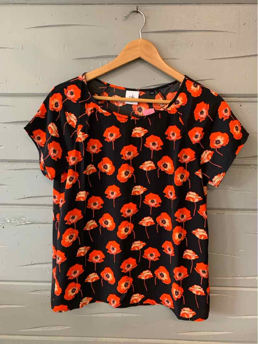 Black short-sleeve blouse with bright orange floral print and round neckline on wooden hanger.