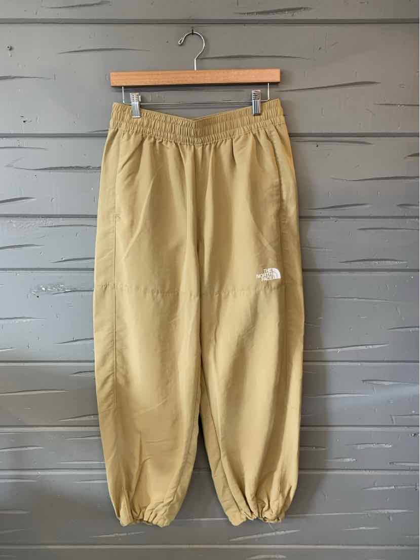 Tan lightweight nylon jogger pants with elastic waistband and cuffs, small white The North Face logo on left thigh.