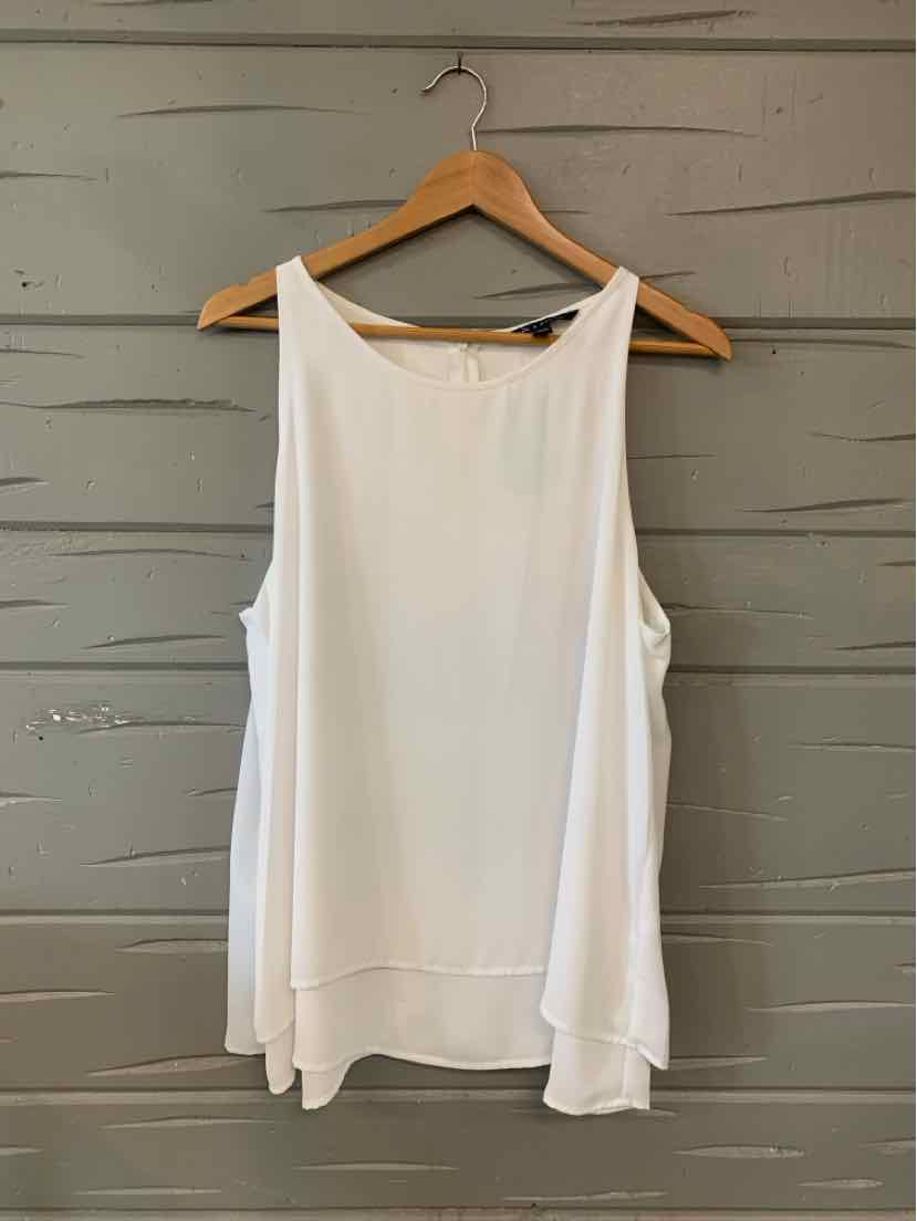 White sleeveless flowy blouse with boat neckline, layered hem, hanging on wooden hanger.