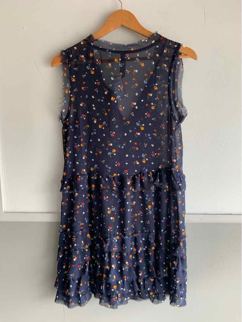 Sleeveless navy blue dress with orange floral print and ruffled tiered skirt on wooden hanger.