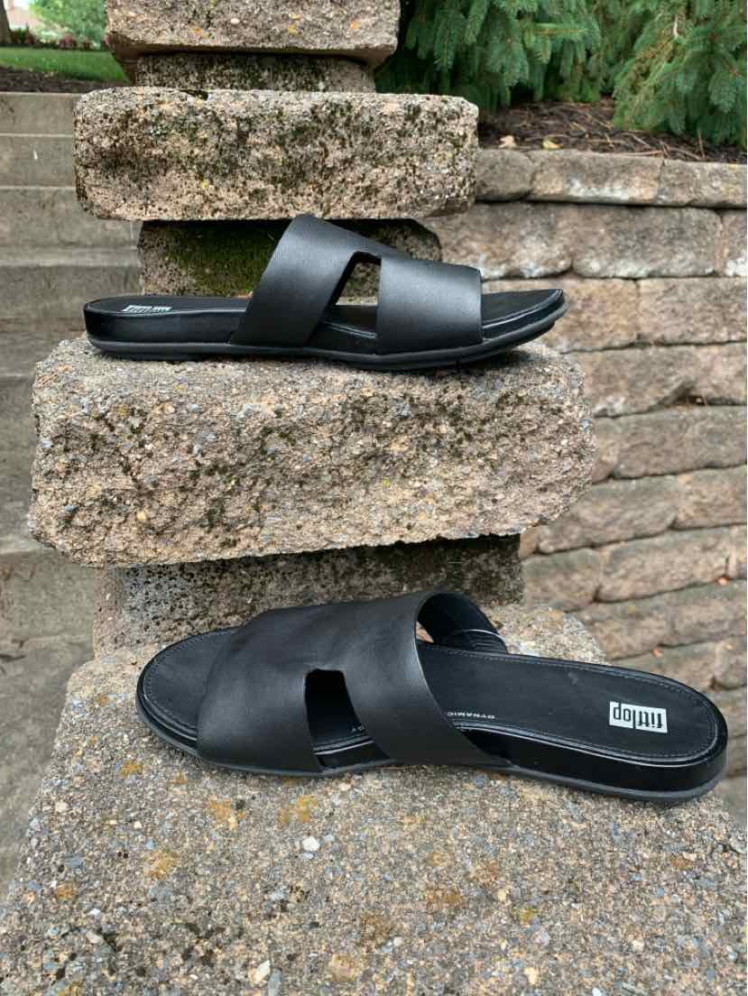 Black slip-on sandals with crisscross wide leather straps and cushioned footbed, size 9.