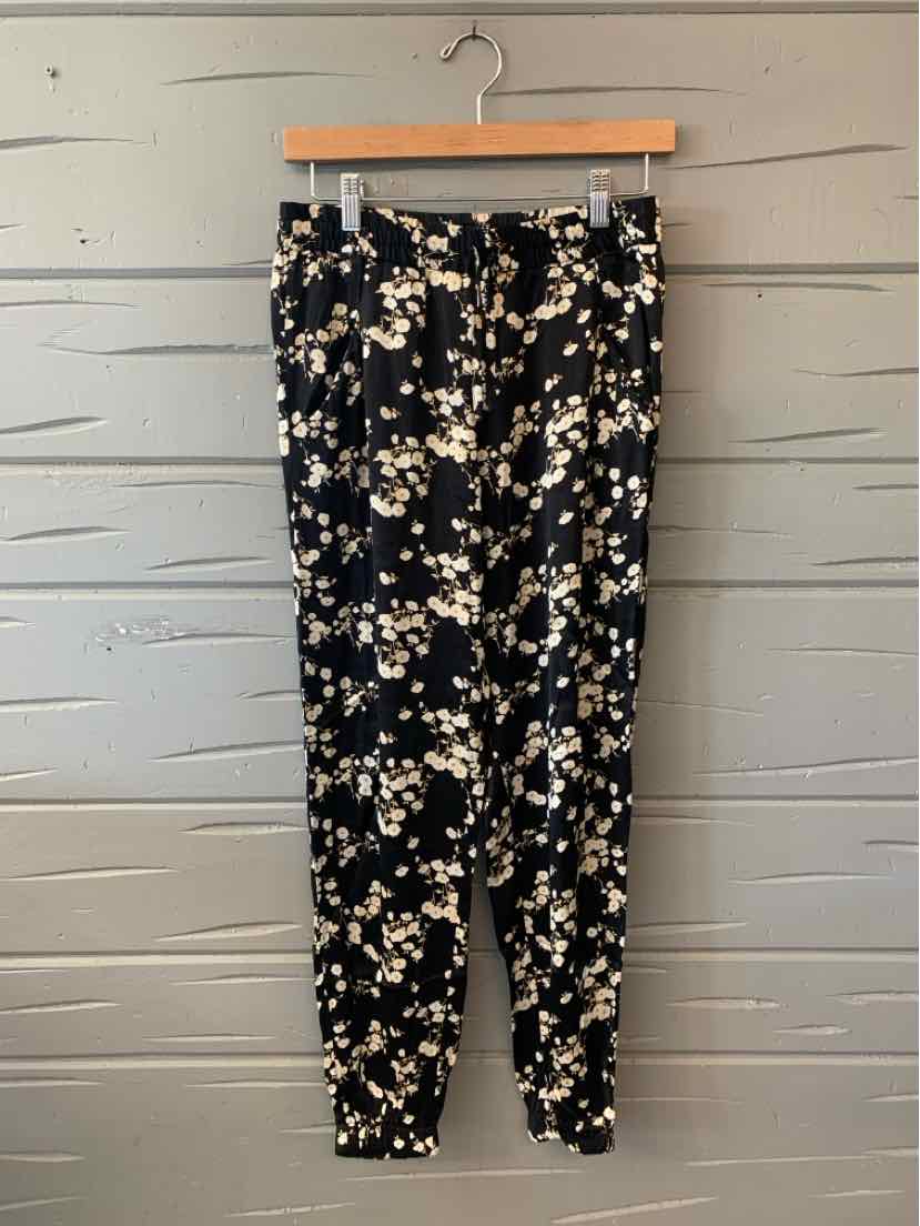 Black tapered pants with white and beige floral print, elastic waistband, and cuffed ankles, size XS.