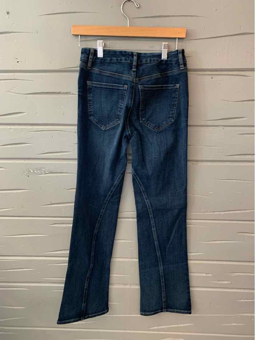 Dark blue denim jeans with straight legs and rear patch pockets hanging on a wooden hanger.
