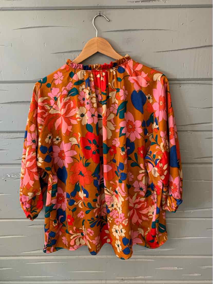 Orange blouse with vibrant multicolor floral print, three-quarter sleeves, and gathered neckline.
