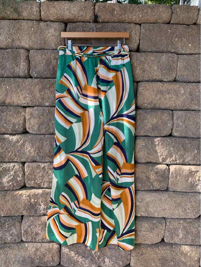 High-waisted wide-leg pants with a green, white, orange, and black abstract swirl pattern and a fabric belt at the waist.