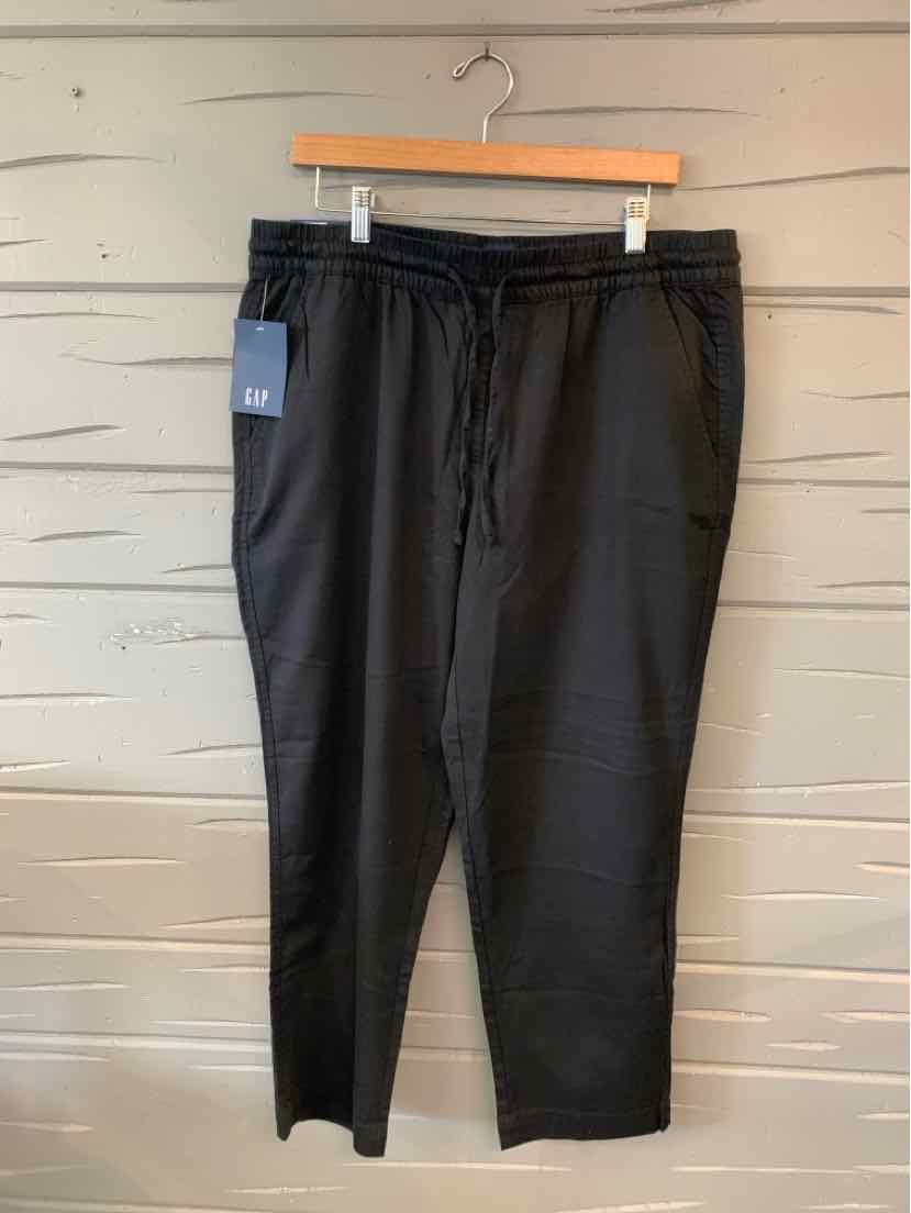 Black relaxed-fit pants with drawstring waist and elastic cuffs hanging on wooden hanger.