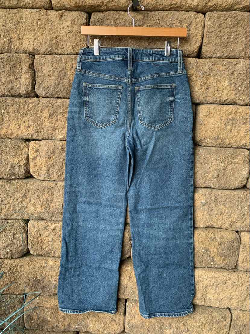 Blue denim jeans with straight legs, back pockets, and slight fades on seat and thighs.
