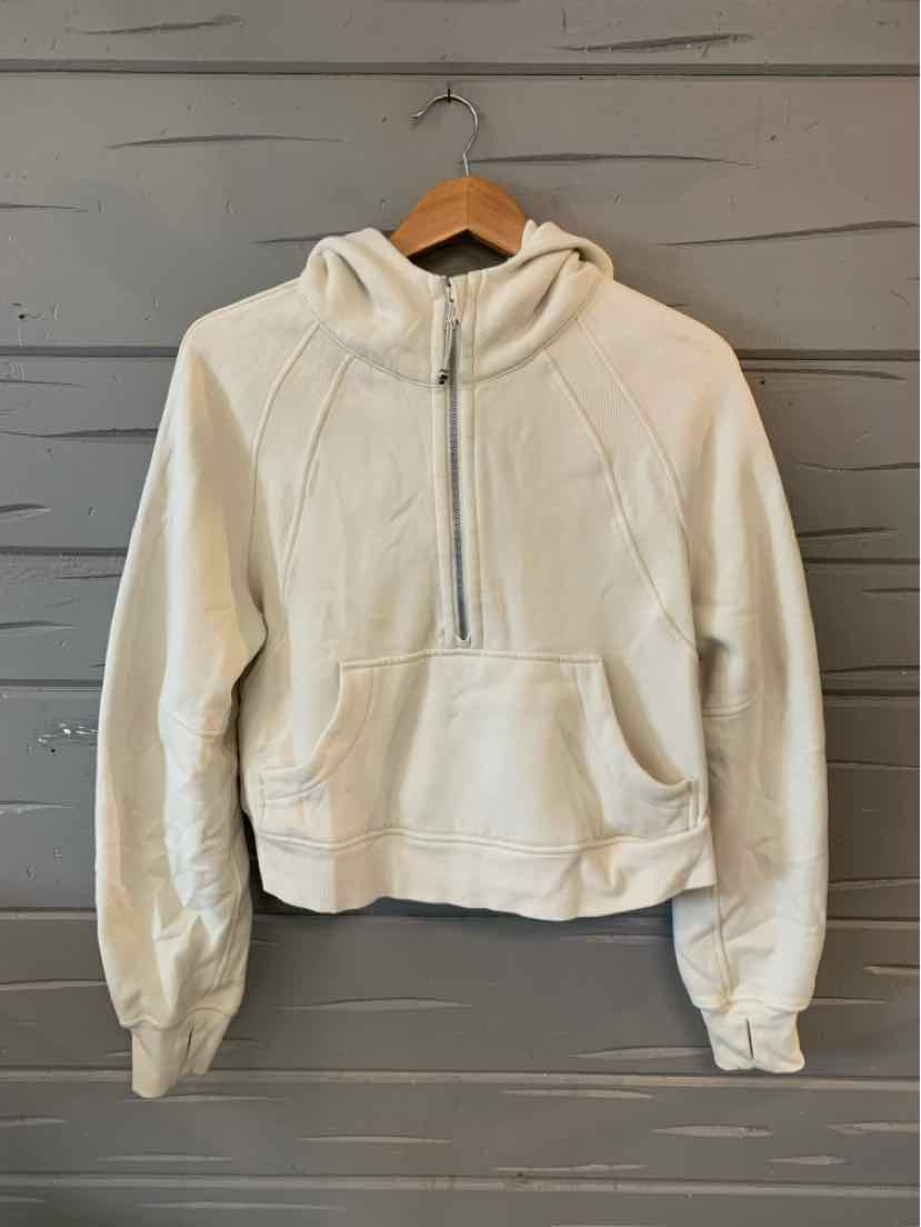 Cream-colored cropped hoodie with front zipper, kangaroo pocket, and long sleeves.