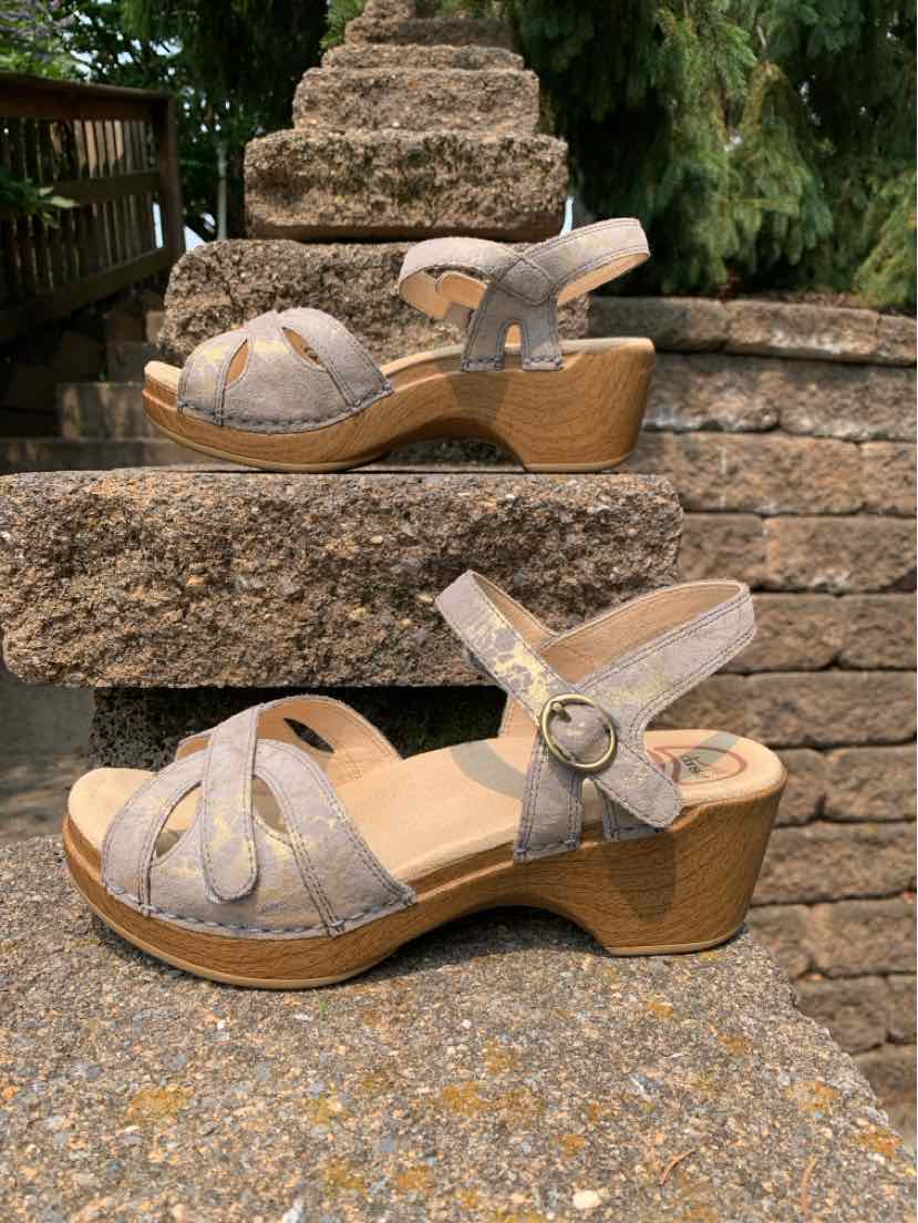 Taupe suede wedge sandals with open toe, ankle strap, and wooden textured heel.