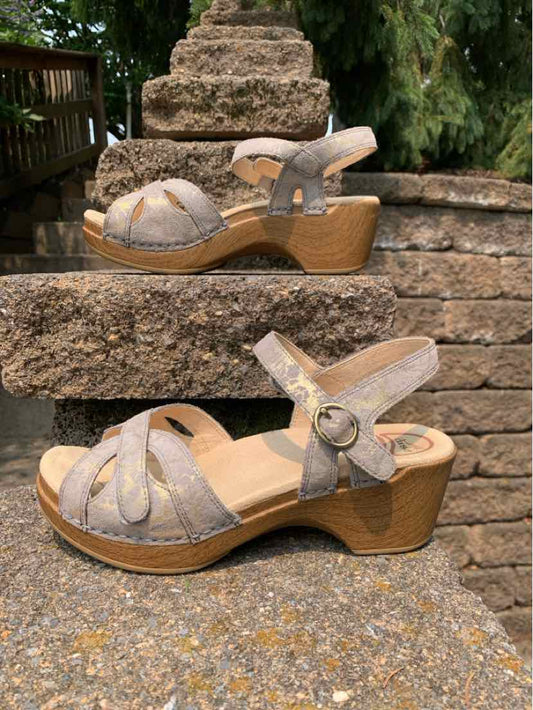 Taupe suede wedge sandals with open toe, ankle strap, and wooden textured heel.
