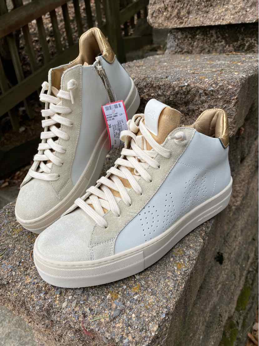 Beige and white leather sneakers with perforated sides, white laces, and beige suede toe caps and heel tabs.