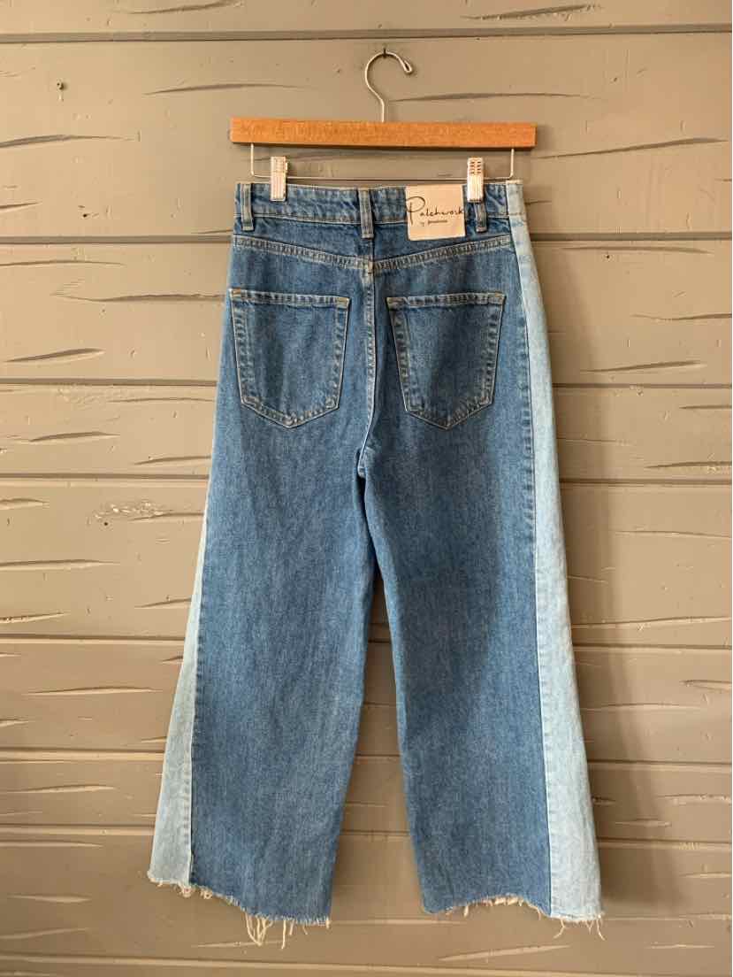 Two-tone denim jeans with a wide-leg cut, featuring medium blue front panels and light blue side panels, back pockets, and a
