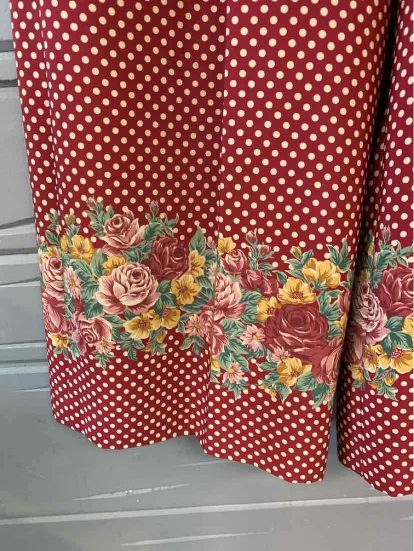 Red fabric with white polka dots and a colorful floral border featuring roses and other flowers.