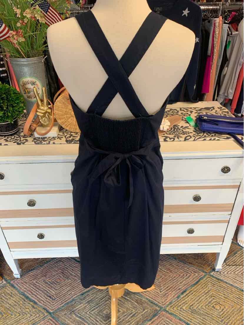 Black sleeveless dress with wide crisscross straps and tied waist bow, knee-length design.