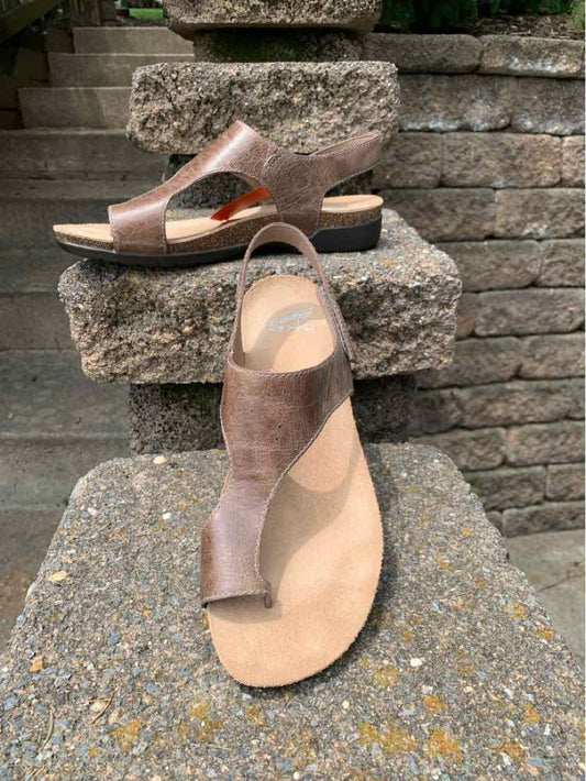 Tan leather sandal with open toe, adjustable ankle strap, and flat sole, size 39.