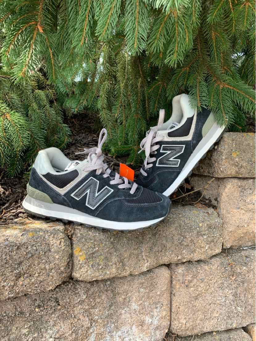 Black and gray New Balance sneakers with white soles and mesh textile accents, lace-up closure.