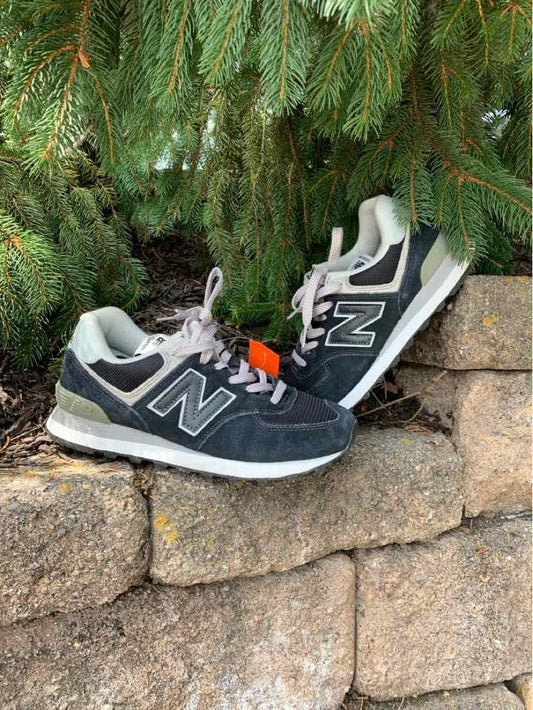 Black and gray New Balance sneakers with white soles and mesh textile accents, lace-up closure.