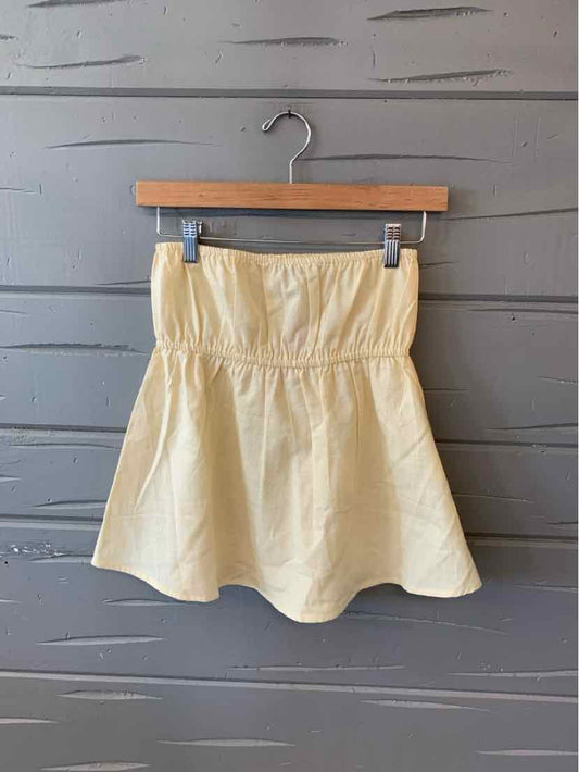 Light yellow strapless dress with fitted bodice and flared skirt, hanging on wooden hanger.