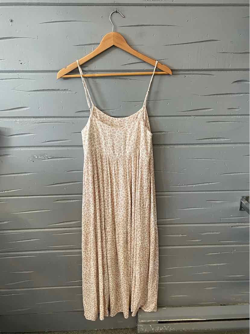 Beige midi dress with cheetah print, thin spaghetti straps, and a flowy skirt hanging on wooden hanger.