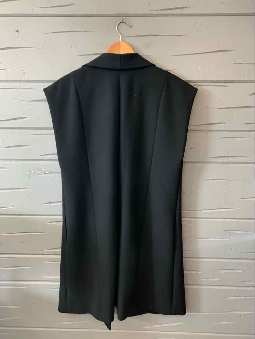 Black sleeveless tailored vest with structured shoulders and long, straight cut hanging on wooden hanger.