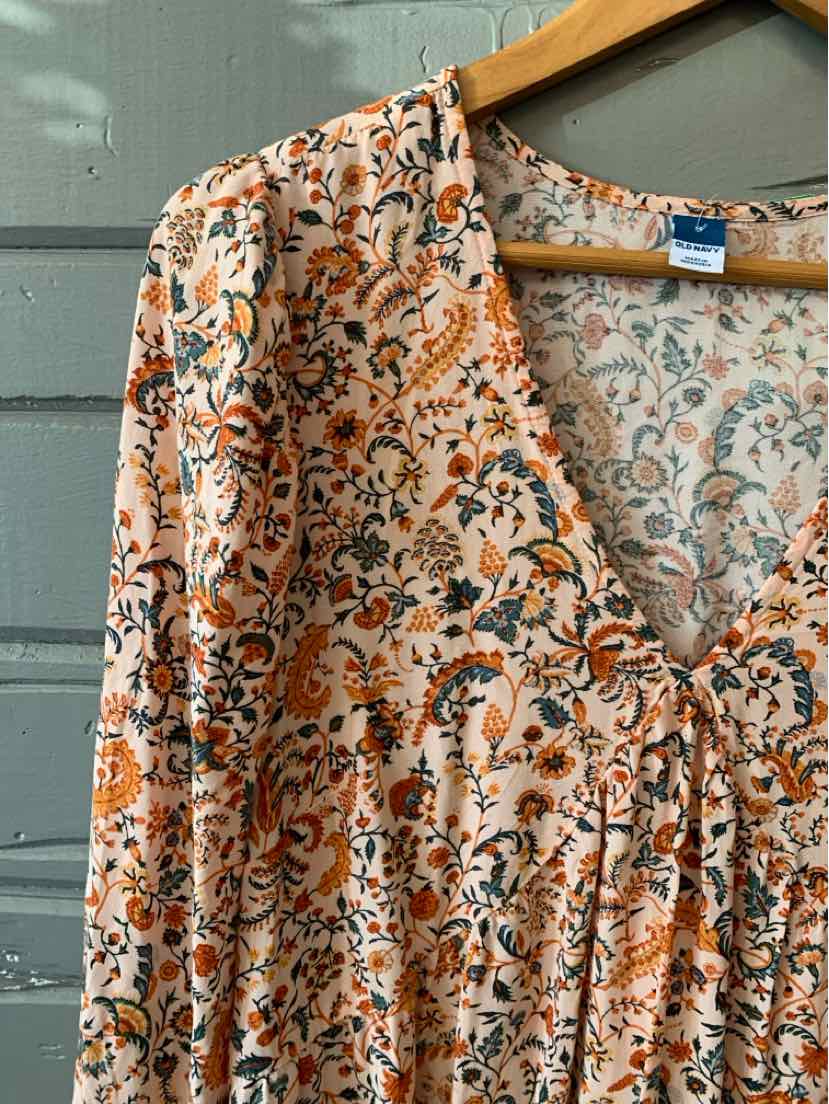 Floral print long-sleeve blouse in peach and white with gathered front detail.