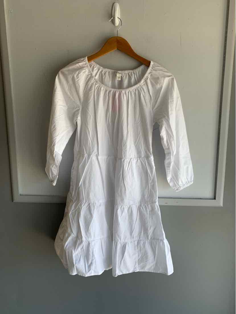 White long-sleeve dress with round neckline and tiered skirt hanging on wooden hanger.
