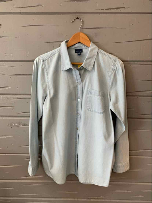 Light blue denim long-sleeve shirt with button-down collar and chest pocket hanging on wooden hanger.