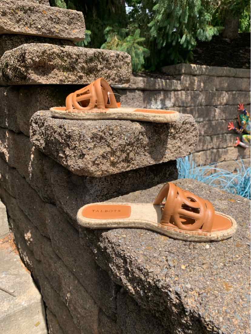 Tan leather flat slide sandals with open toe and decorative cutout strap design.