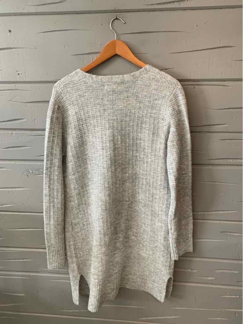 Light gray long-sleeve knit sweater with side slits, crew neckline, and relaxed fit hanging on wooden hanger.