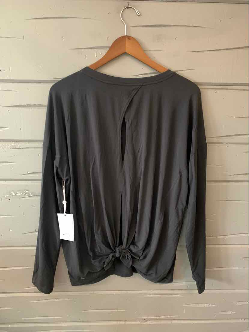Black long-sleeve top with knotted detail at the back hem, hanging on a wooden hanger.