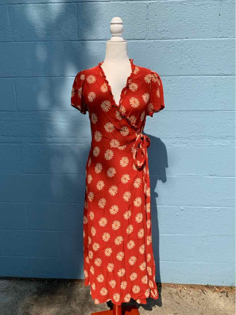 Red wrap dress with white floral print, short sleeves, and V-neckline on mannequin.