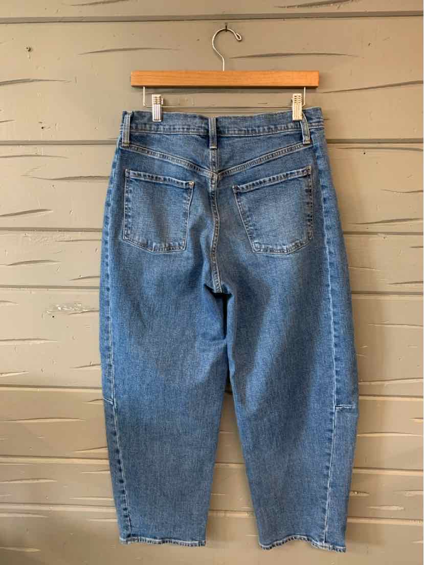 Blue high-waisted denim jeans with a straight leg cut and back pockets hanging on a wooden hanger.