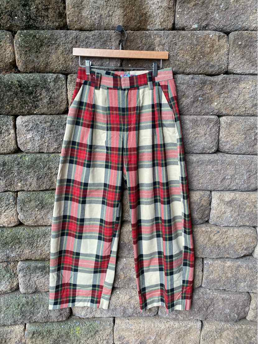 High-waisted plaid pants in red, white, and green with wide legs and a belt at the waist.