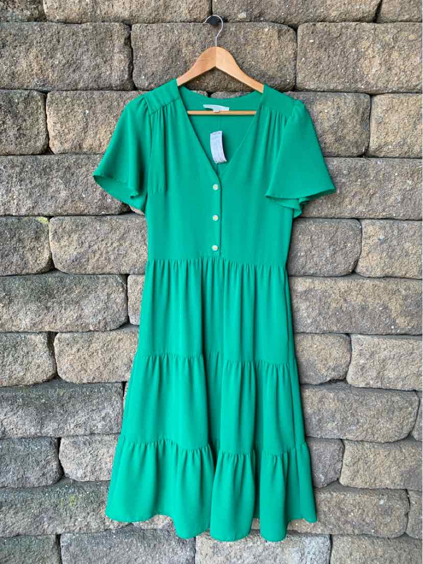Green short-sleeve midi dress with buttons down front and tiered skirt on wooden hanger.