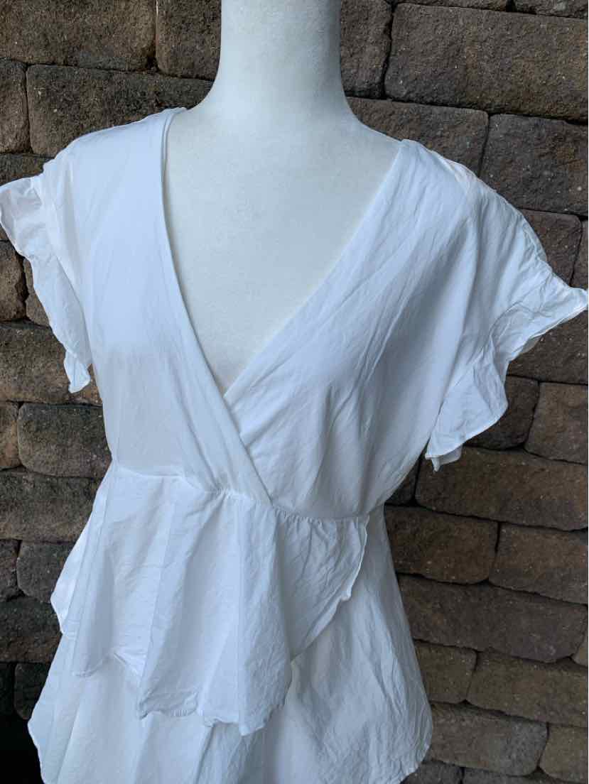 White short-sleeve wrap dress with ruffled edges and lightweight fabric on mannequin.
