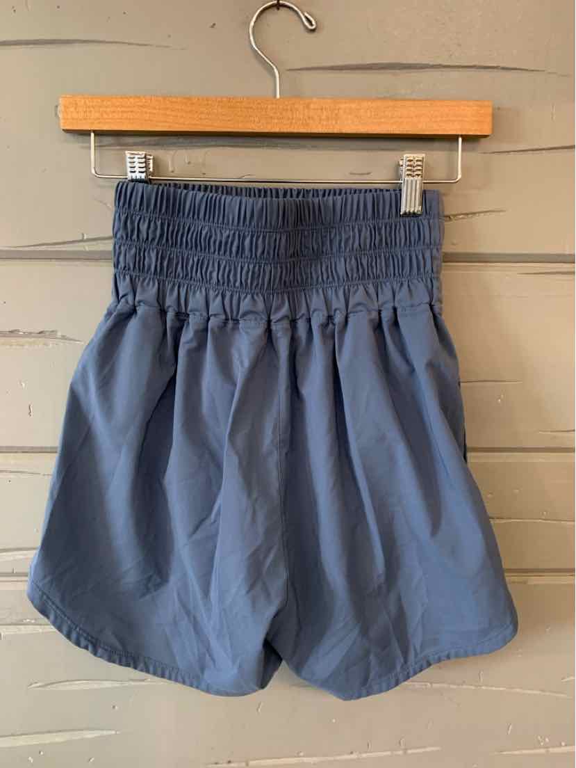 Navy blue Nike shorts with wide elastic waistband and loose fit hanging on wooden hanger.