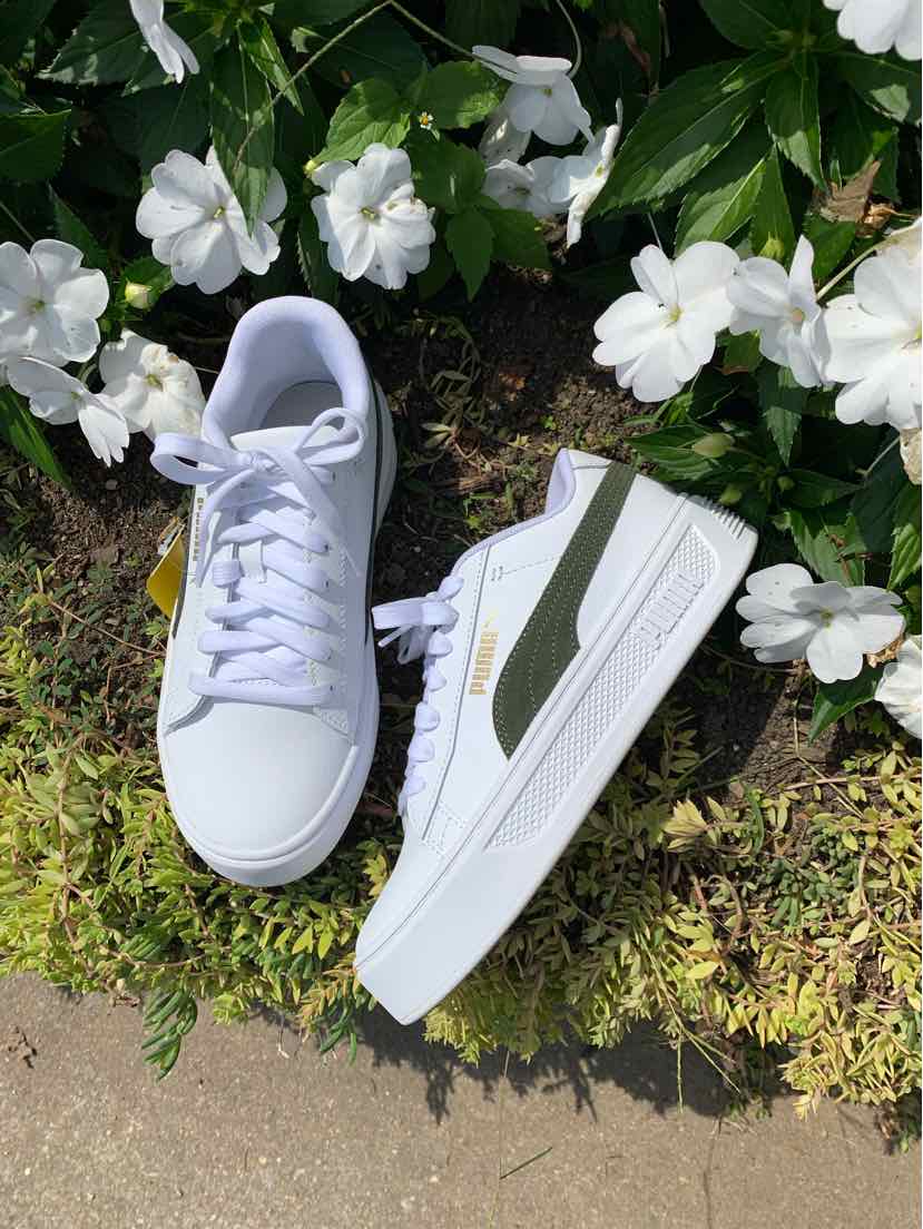 White low-top Puma sneaker with olive green stripe, white laces, and rubber sole, size 7.