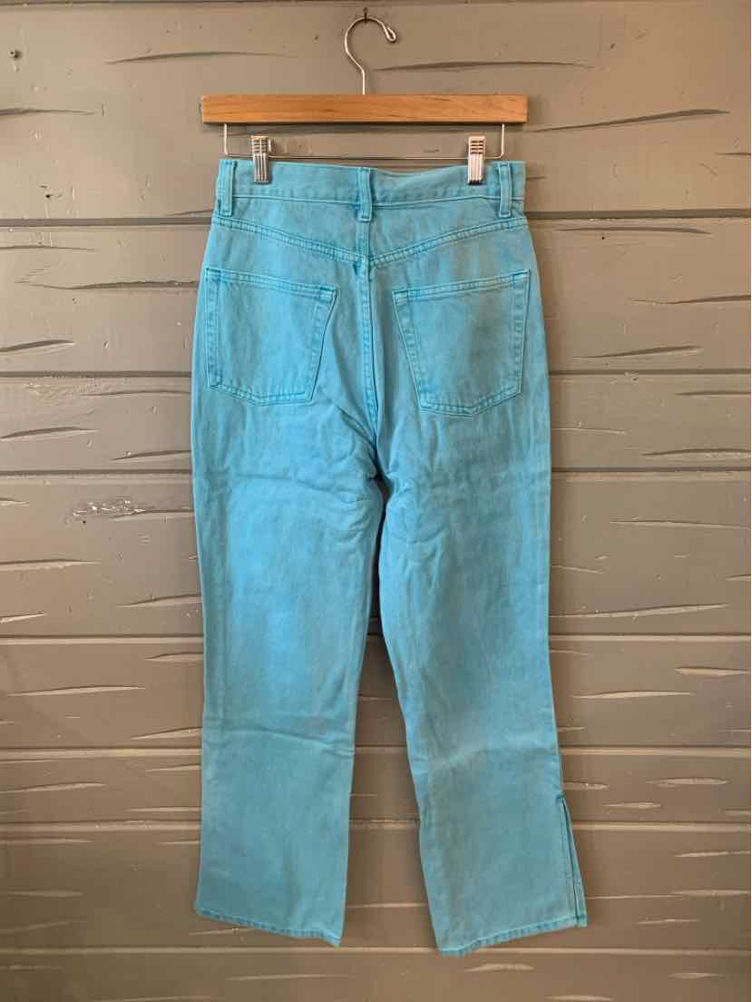 Light blue denim jeans with back pockets and straight-leg cut hanging on wooden hanger.