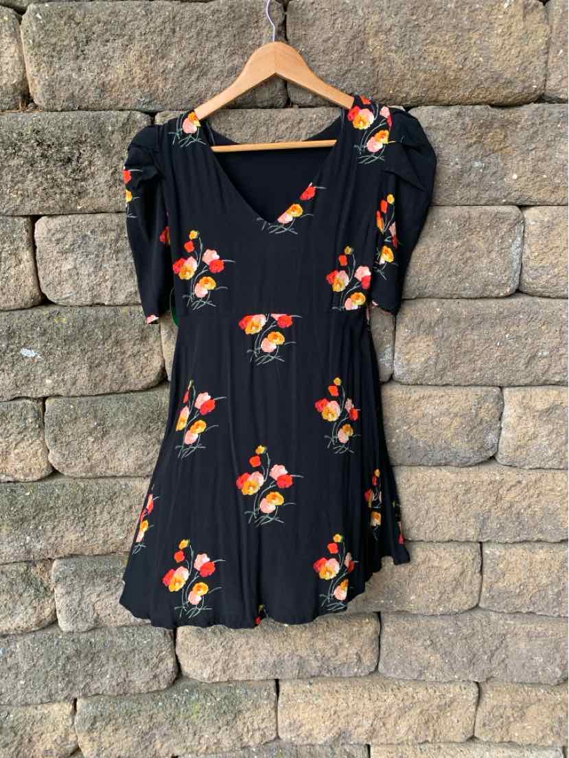 Black short-sleeve dress with floral print and V-neck on wooden hanger.