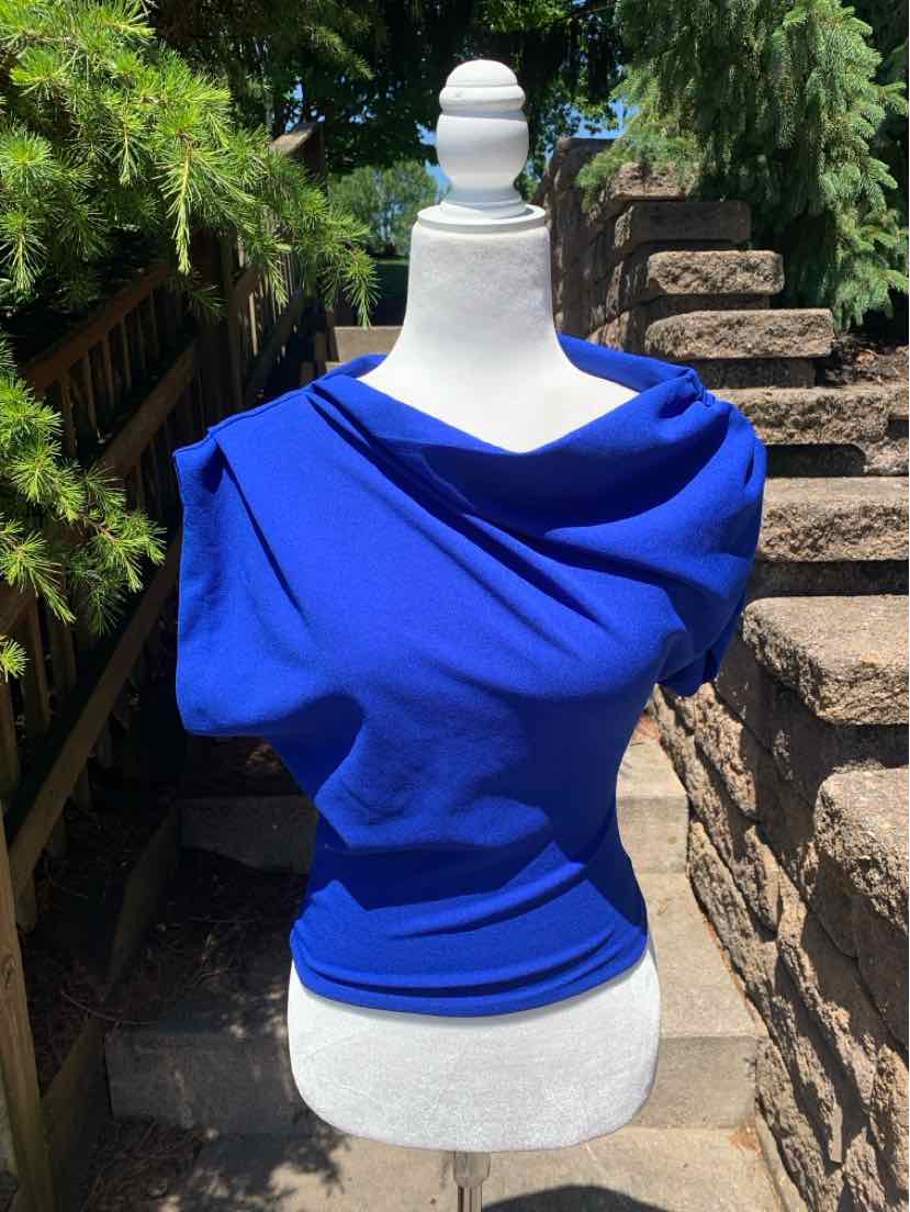 Bright blue asymmetrical off-shoulder top with draped neckline and fitted waist on mannequin.