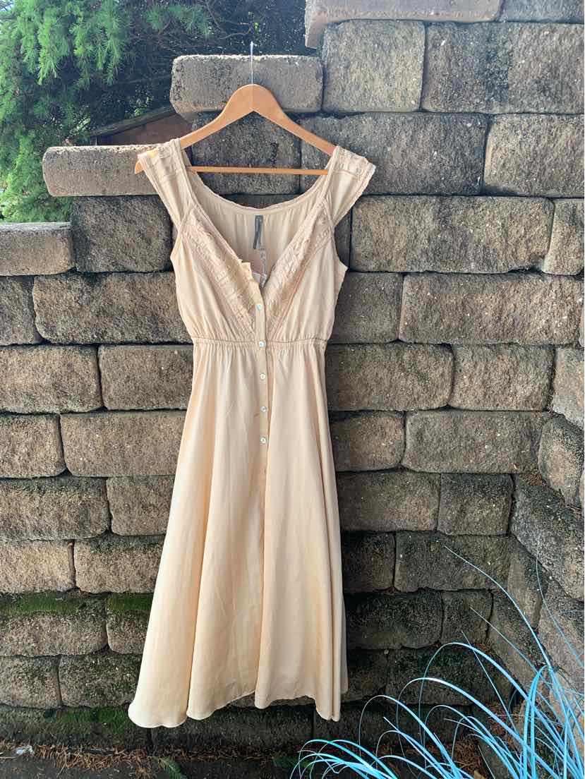 Tan sleeveless midi dress with V-neckline, button front, and fitted waist on wooden hanger.