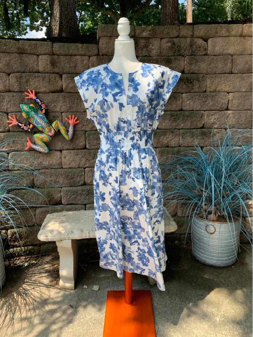 Blue and white floral sleeveless midi dress with cinched waist and round neckline.