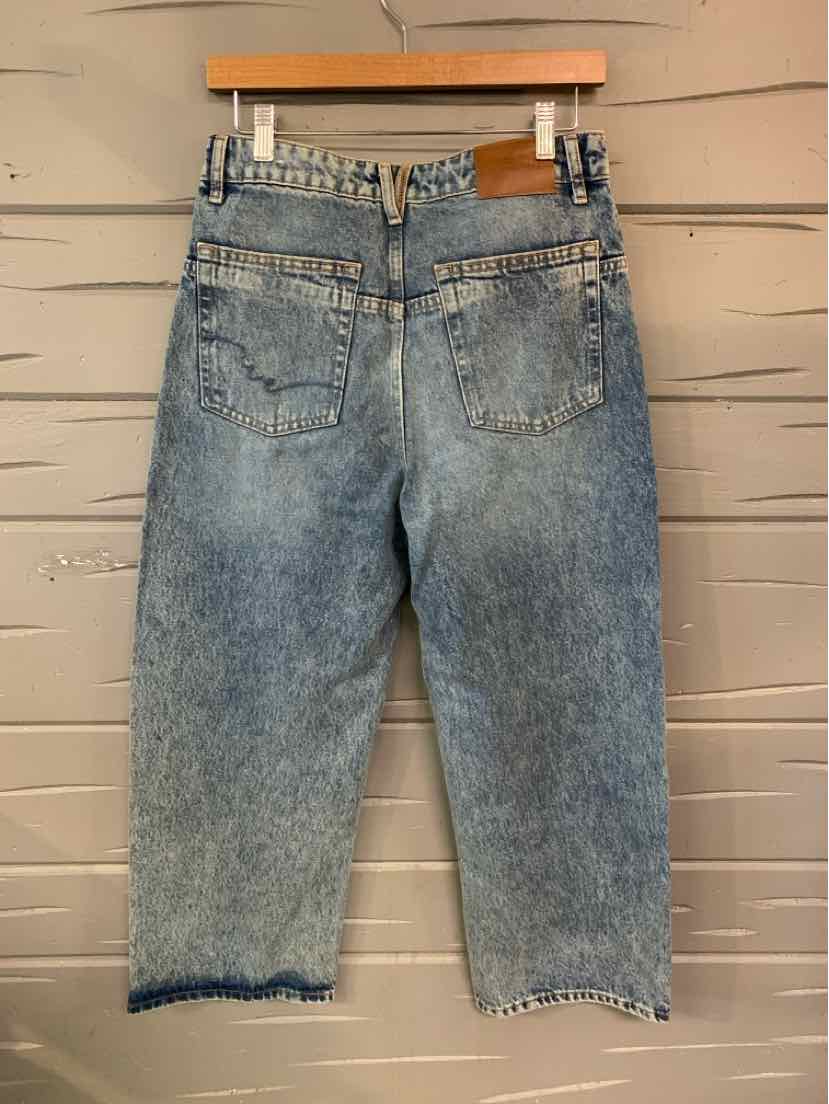 Light blue high-waisted denim shorts with frayed hems and two back pockets hanging on a wooden hanger.
