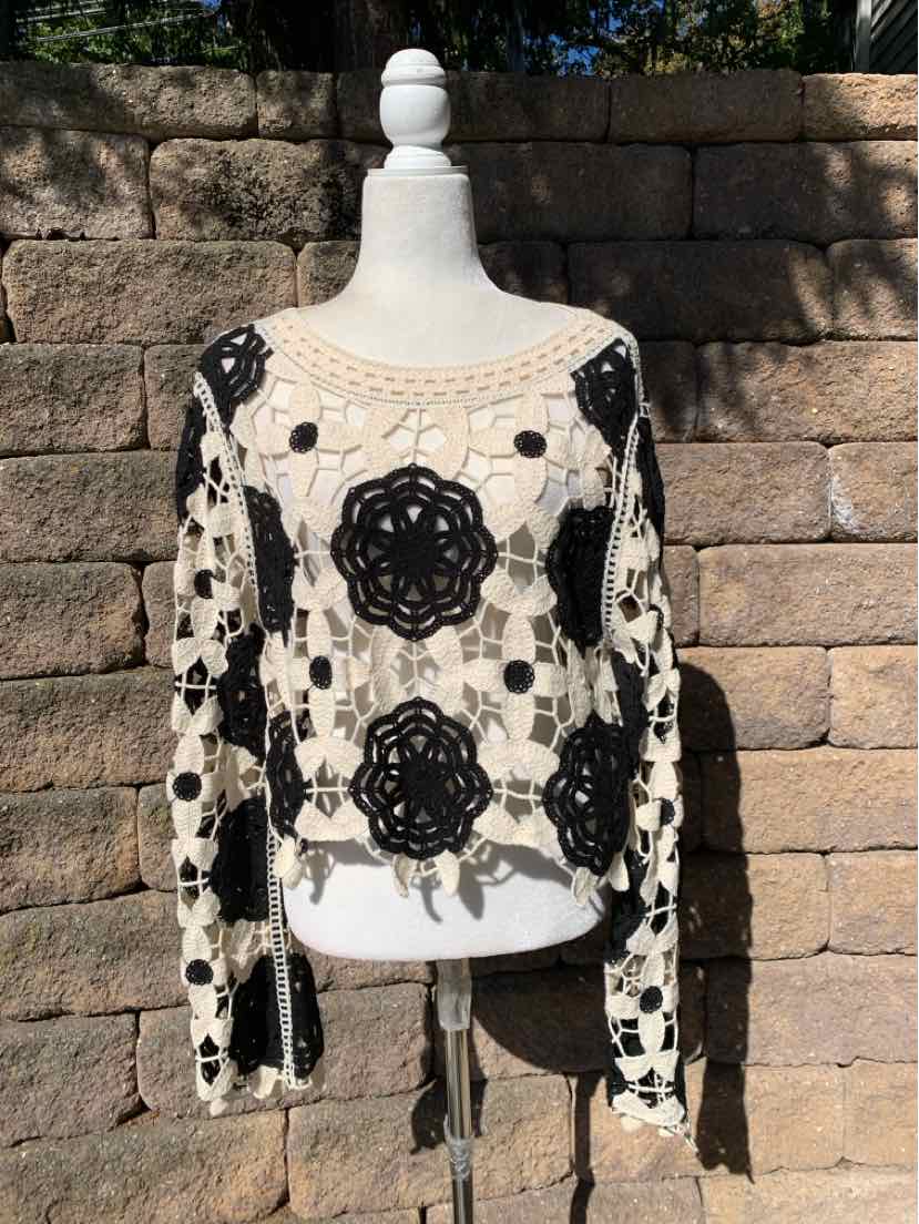 Black floral lace overlay on a cream long-sleeve top, displayed on a mannequin.