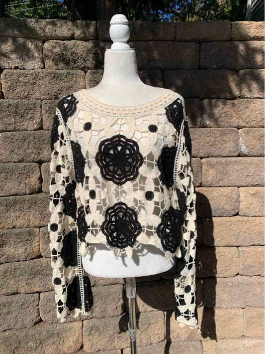 Black floral lace overlay on a cream long-sleeve top, displayed on a mannequin.